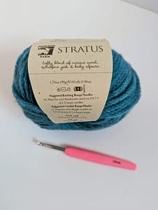 Pink handle crochet hook and a ball of blue coloured yarn
