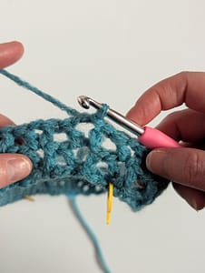 Close up of crochet V stitch in blue yarn
