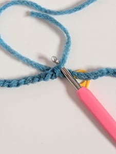 close up of a crochet hook and chain stitches in blue yarn