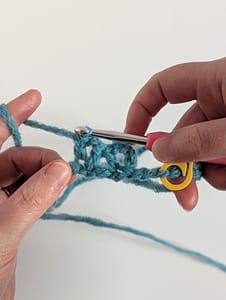 Two hands holding a close up piece of crochet in V stitch pattern