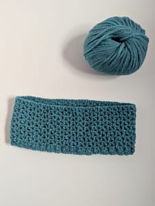 Finished V stitch pattern crochet cowl in blue yarn on a white background