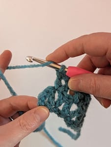 Two hands and a crochet hook ready to work the next stitch