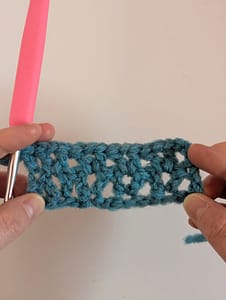 Two hands holding a piece of crochet worked in V stitch pattern