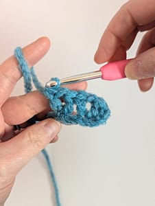 piece of crochet in blue yarn, with 2 V stitches already worked