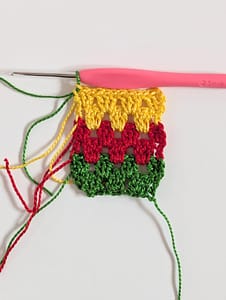 Six rows of crochet in granny stripe pattern in green, red and yellow yarn