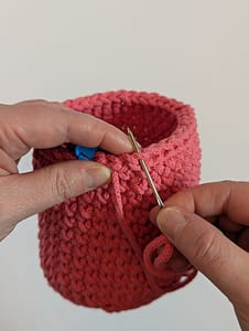 Thread yarn tail through back loop of previous stitch