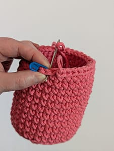 Thread yarn tail under both loops of next stitch