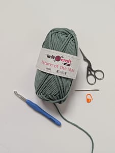 A ball of yarn, a crochet hook, stitch marker, yarn needle and embroidery scissors