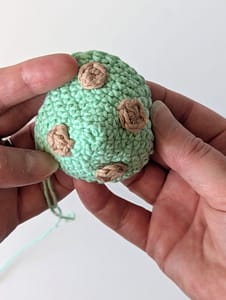 A curved crochet fabric in mint green color with brown crochet dots, to represent the top of an ice cream