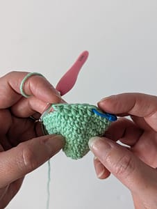 Two hands holding a crochet cone shape in mint green yarn