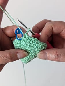 Two hands holding a crochet cone in mint green yarn