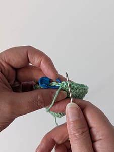 A yarn needle being threaded through a crochet stitch