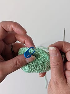 Two hands holding a crochet item made in mint green yarn