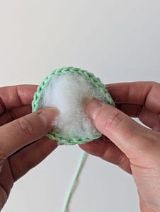 Toy stuffing being placed inside a piece of crochet in Mint Green