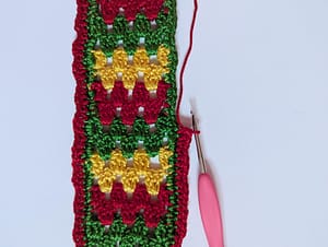Crochet bookmark in granny stripe pattern, with the red border being crocheted