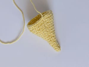 A crocheted cone in yellow yarn, made with single crochet stitches