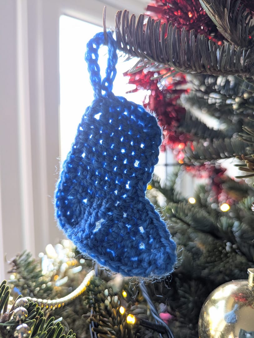 Blue crocheted stocking Christmas tree decoration, hanging on a Christmas tree