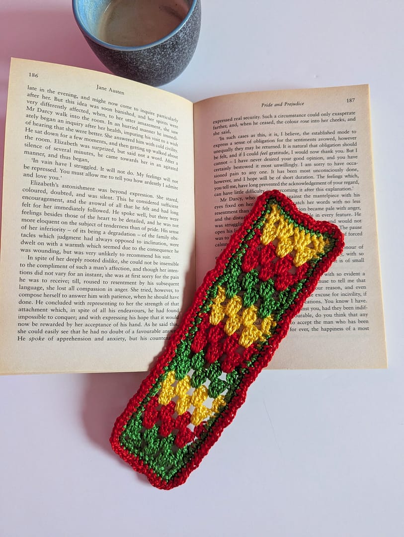 Crochet bookmark in granny stripe pattern on a book with a cup of coffee